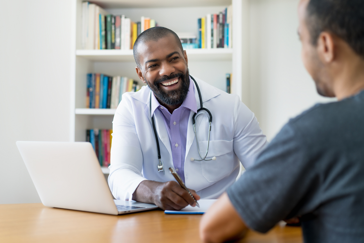 Laughing mature adult African American male doctor listening to patient